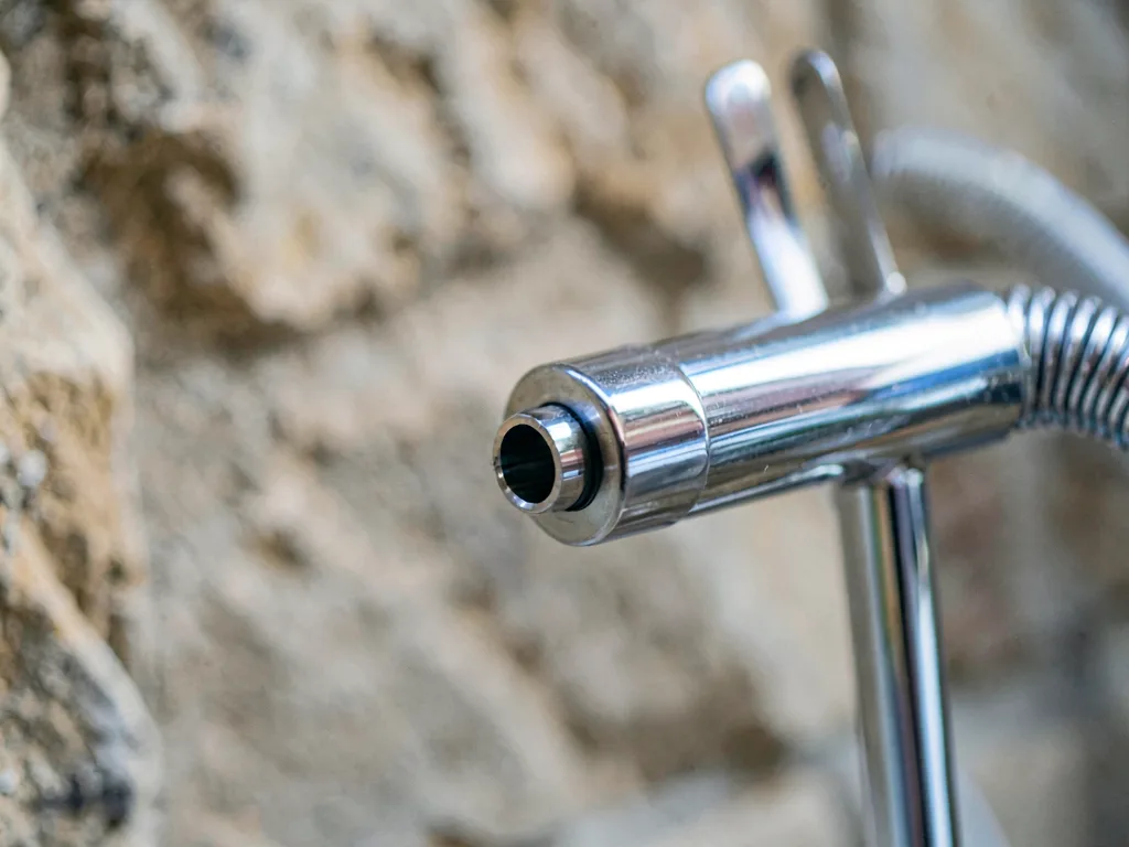 The nozzle of a stand dryer on its chrome arm, close up